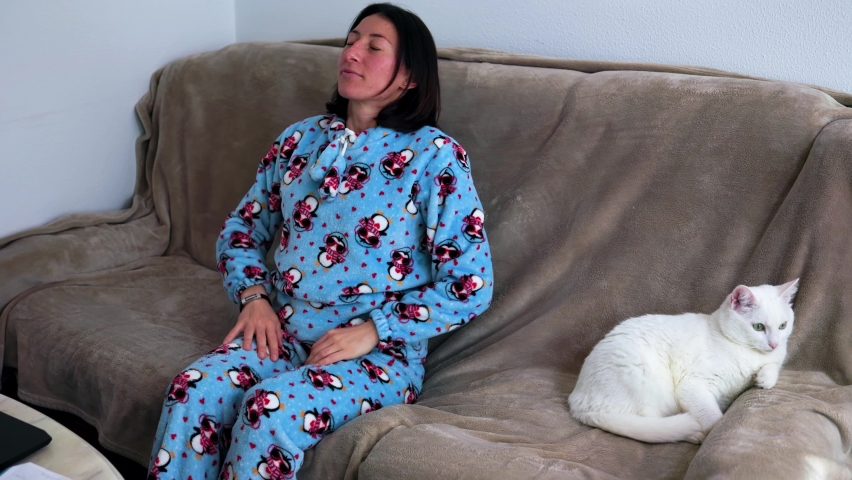 a girl in blue pajamas leans back on the couch and sighs Royalty-Free Stock Footage #1089089799