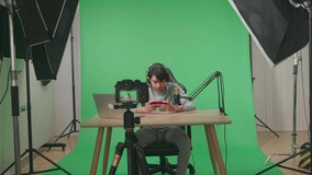 A Camera Recording Asian Man Gamer With Headphone And Computer Using Mobile Phone Playing Game On The Green Screen Background With Professional Light Equipment
