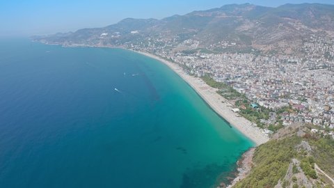 Alanya beach top view on the mountain with coast on blue sea and harbor city background. Beautiful cleopatra beach Alanya Turkey landscape travel landmark. Top view from drone 