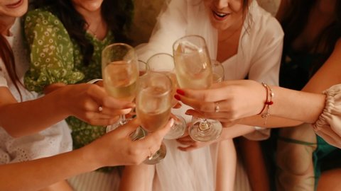 Wedding morning bride. Bridesmaids clink with champagne. toasting glasses champagne wine celebrating bridal shower hen bachelorette birthday spa party together hotel. Close up clinking glasses cheers