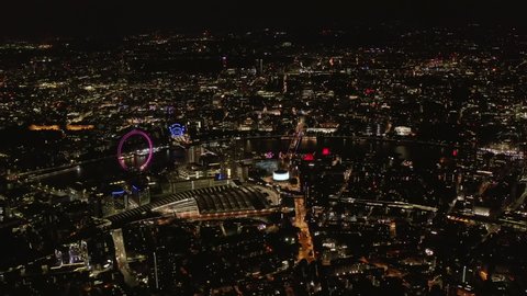 High angle view of Waterloo train station and London Eye at Thames river bank. Aerial panoramic shot of city at night. London, UK in 2021