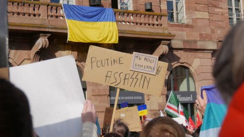 Strasbourg, France - February 26, 2022: People with Ukrainian flags and posters protest against the war in Ukraine. Demonstration against the war between Ukraine and Russia. Protests against Putin