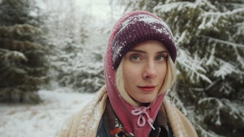 Portrait of young beautiful woman posing for camera in winter woods