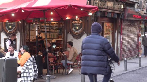 Madrid, Spain- March 2022: La Casa Del Abuelo a popular cafe taberna with loutdoor tables, central Madrid, Spain. Tourists, waters in face masks walking in winter city. Travel