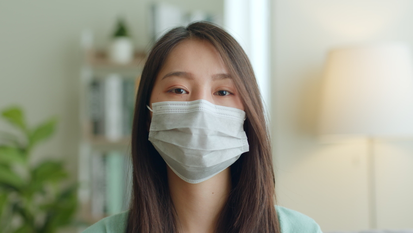 Young Asian woman takes off protective mask and look at camera after coronavirus pandemic end with smile Royalty-Free Stock Footage #1089102017