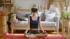 Peaceful clam asian female woman wearing virtual reality glasses meditating at home in breath train hands in namaste enjoying simulation and relax. Virtual  technology experience in metaverse world - Powered by Shutterstock - Get 15% off with code: PIKWIZARD15