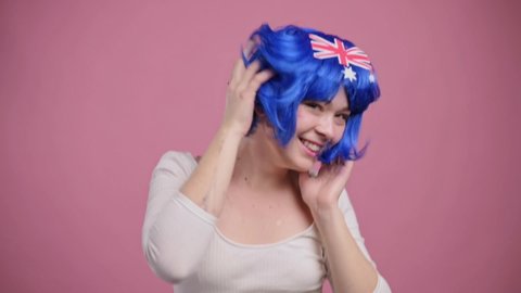 Australian patriot woman. Portrait of young smiling dancing female in wig with national symbols of Australia.