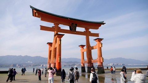 Miyajima, Japan - Apr 23, 22: People walking in front of the great Torii of Miyajima also know as the floating Torii during summer. High quality footage.