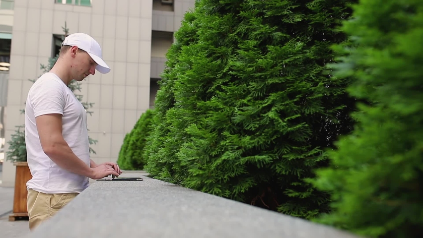 A man uses a tablet on the street in the summer