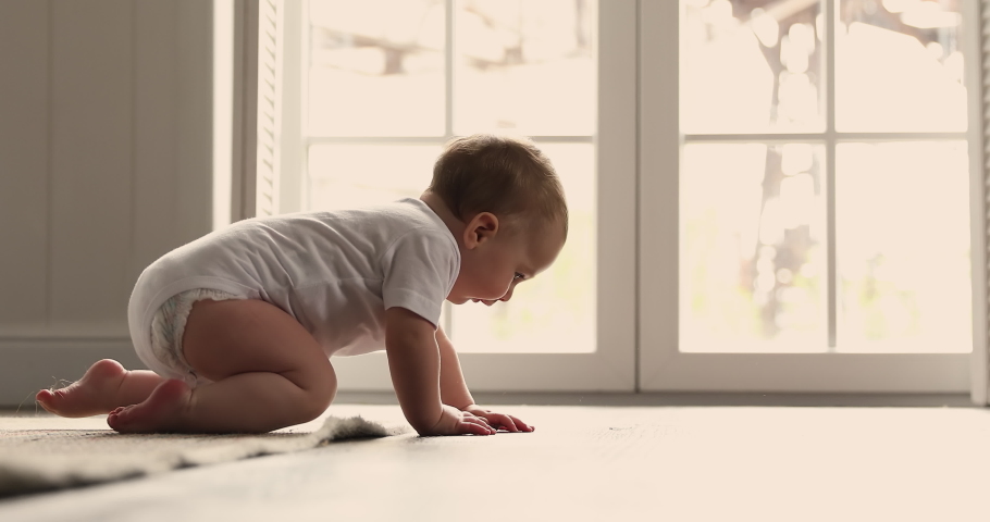 Energetic little baby boy girl about 6 months dressed in diaper white cotton singlet move crawl by warm wooden floor with underheating. Funny babe child make first attempts to discover world around Royalty-Free Stock Footage #1089117335