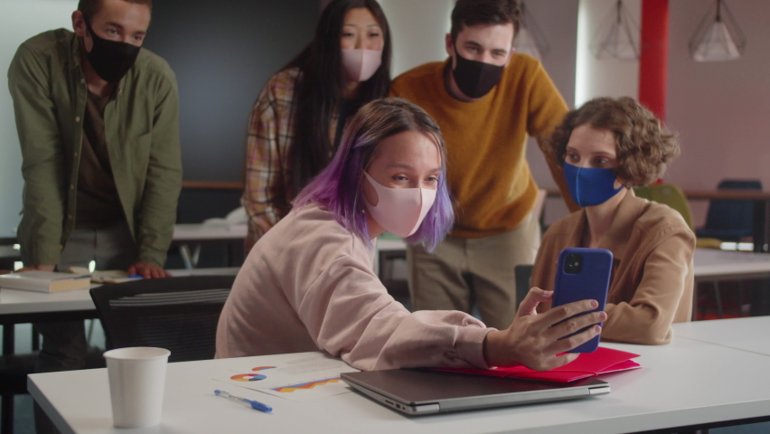 Five energetic young classmates in the audience in the university finish talking with their friends on the video call, slow motion