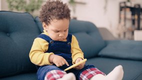 Serious African American baby playing on smartphone, looking bossy and funny