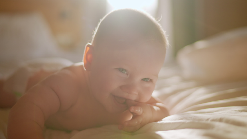 Beautiful Smiling Baby, gorgeous little baby lie on bed and smile at camera with nice soft focus background. Little girl or boy is humming, real original audio track, lovely asian baby playing at home Royalty-Free Stock Footage #1089121093