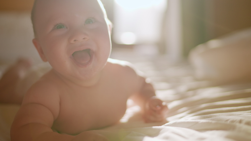 Beautiful Smiling Baby, gorgeous little baby lie on bed and smile at camera with nice soft focus background. Little girl or boy is humming, real original audio track, lovely asian baby playing at home | Shutterstock HD Video #1089121093