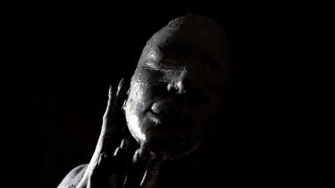 scary movie concept, figure of woman blindfold and covered by clay in darkness, medium portrait shot