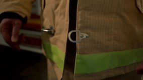 Close up of firefighter putting on a body safe suit uniform for protection from fire operation. Clip. Male fireman fastening the buttons of his suit.