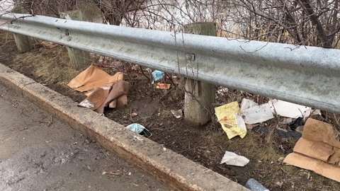 Garbages left on the side of a road polluting nature. MONTREAL, CANADA, APRIL 2022