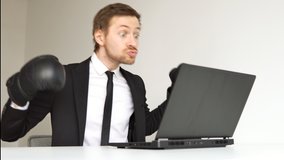 Young angry businessman in black suit wearing boxing gloves using laptop. - Powered by Shutterstock - Get 15% off with code: PIKWIZARD15