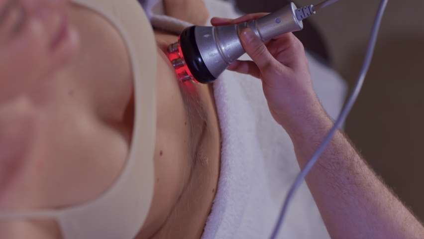 procedure removing cellulite on female abdomen, cavitation belly massage. Ultrasonic massage for weight loss. Correction of female figure without surgical intervention. Closeup of the tummy.