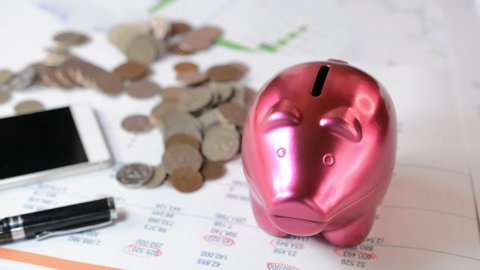 Putting a coin in a piggy bank close