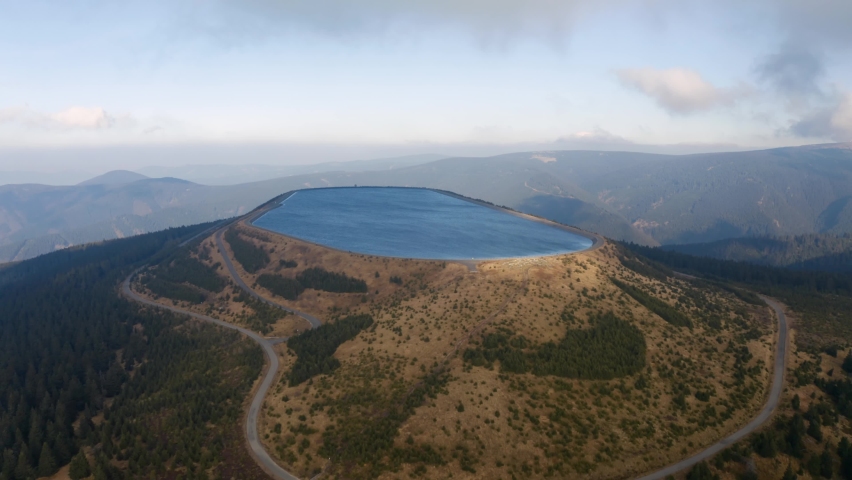 Elevated water reservoir pumped energy storage hydro power plant, storing energy in water when there is excess on the electric grid, and releasing at peak hours. Mountain top basin | Shutterstock HD Video #1089128625