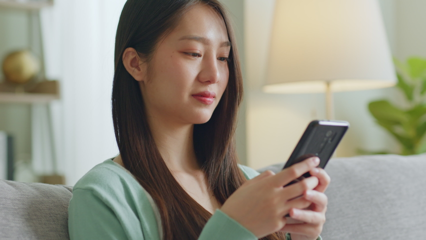 Young Asian woman with smile using smartphone for social media, shopping online, playing game at home feeling happy Royalty-Free Stock Footage #1089128649