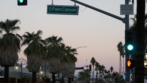 Palm trees and sky, Palm Springs street, city near Los Angeles, semaphore traffic lights on crossroad. California summer road trip on car, travel USA. Road sign Palm canyon, twilight dusk after sunset