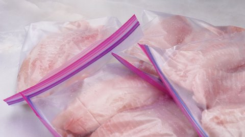 Fresh raw fish fillet in zip lock bags. Tilapia fillet on light marble background, close up view