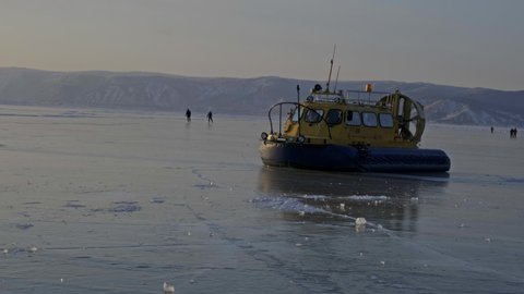 Hovercraft on frozen ice surface of the Baikal lake at sunset. Khivus - transport on ice, 4k