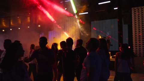 Mariupol, Ukraine - 15 June 2019. People are dancing in Barbaris night club lit by show lights. Silhouettes of men and women partying on dance floor in slow motion. Ordinary open entry weekend party.