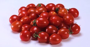 Close-up side view 4k stock video footage of red organic tomatoes isolated on light white  background spinning around slowly