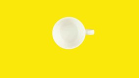 White cup on yellow background is filled with coffee beans, emptied, filled with coffee drink again and drunk. Looping stop motion animation. Copy space for your text.