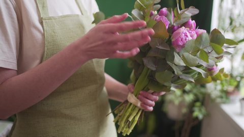 Professional florist checks a beautiful bouquet before sending it to the customer. Fresh flowers in the hands of a young woman close-up. The concept of small business and women entrepreneurs