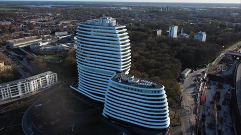 GRONINGEN, NETHERLANDS - 09. APRIL 2022: Aerial orbiting shot of modern office building, head of dutch tax authorities. Cruise ship building at Kempkensberg.