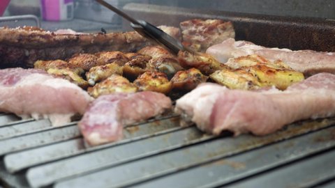 closeup seasoning various meats on the grill with the bristles of a brush in the day in 4k
