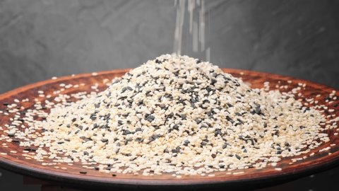 White and black sesame seed falling in a plate. Slow motion shot. 4k