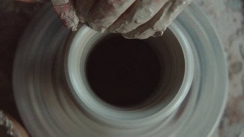 Top down close up shot of hands of unrecognizable male artisan throwing vase on pottery wheel