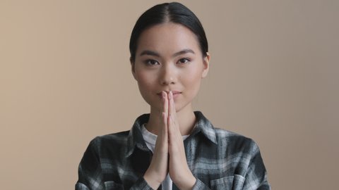 Close up portrait asian calm girl folds palms in front bows namaste greeting prays. Chinese woman asking for forgiveness apology gesture hope spiritual praying with folding hands