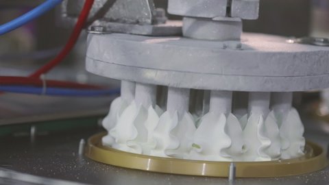 Automated production of ice cream. Automated conveyor for creating an ice cream cake. Ice cream nicely squeezed out of the tubes
