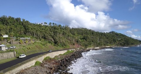 Wild coast of Dominica Island and the road with passing cars, Caribbean Sea