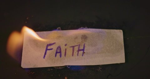 Closeup video of burning paper with FAITH written on it