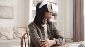 Beautiful young girl wearing virtual reality headset. Augmented Reality. Happy cute woman touch something using modern 3D vr glasses indoors. Woman playing using VR goggles at home office. Shot on 4K 