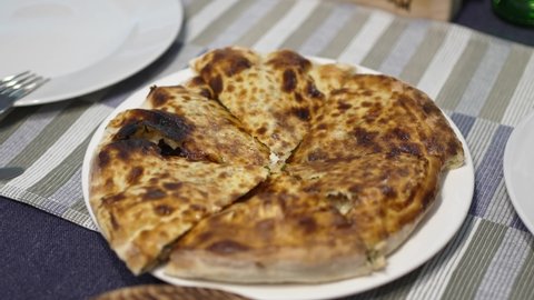 a woman takes a piece of flatbread with cheese and herbs. traditional Georgian dish. pie with filling. closed pizza.