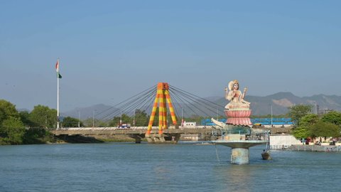 Haridwar, Uttarakhand, India - 10th April 2021 : View of Haridwar bridge over river Ganges, Har Ki Pauri Ghat on the banks of Holy river Ganges, with blue sky and Himalayan mountains in background.