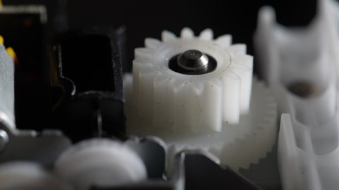 Gears rotating in a mechanical device. Machine white plastic gears rotating abstract. Cog wheels machinery, close up, macro