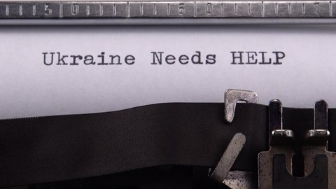 Typing phrase "Ukraine Needs HELP" on retro typewriter.