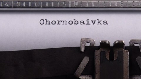 Typing name of village in the Kherson region of Ukraine "Chornobaivka" on retro typewriter.