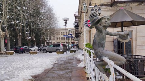 Kutaisi, Georgia - March 17, 2022: Famous sculpture of young man with hats on White Bridge over Rioni river.