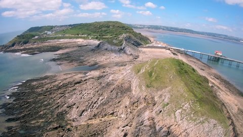 Aerial view of Bracelet Bay the Gower Peninsula South Wales with Mumbles lighthouse, Swansea city, Fpv drone footage
