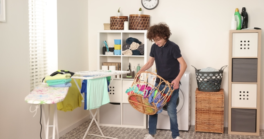 Boy is playing with clothes during laundry. Young teen boy throwing basket with laundry | Shutterstock HD Video #1089164453